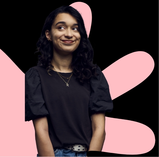 A person wearing a dark top stands against a black background with large pink abstract shapes behind them.