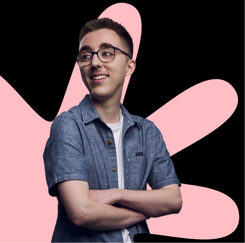 A person with arms folded stands against a black background with large pink abstract shapes behind them.